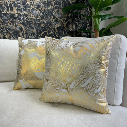 Cojín decorativo cuadrado 45x45 cm con diseño de hojas doradas, en tela bouclé sobre sofá moderno
